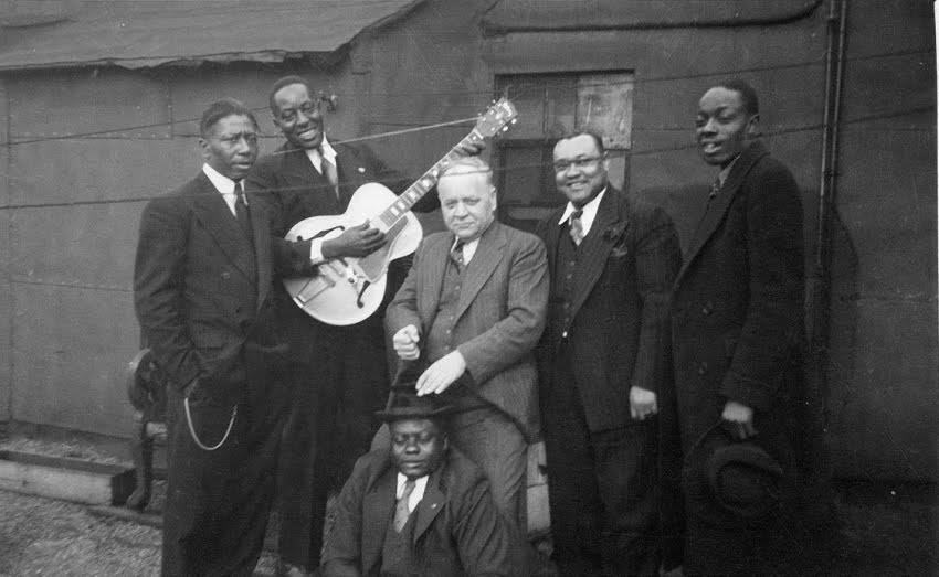 From left: Ernest 'Little Son Joe' Lawlars, Big Bill Broonzy, Lester Melrose, Roosevelt Sykes, St. Louis Jimmy Oden. Front: Washboard Sam.