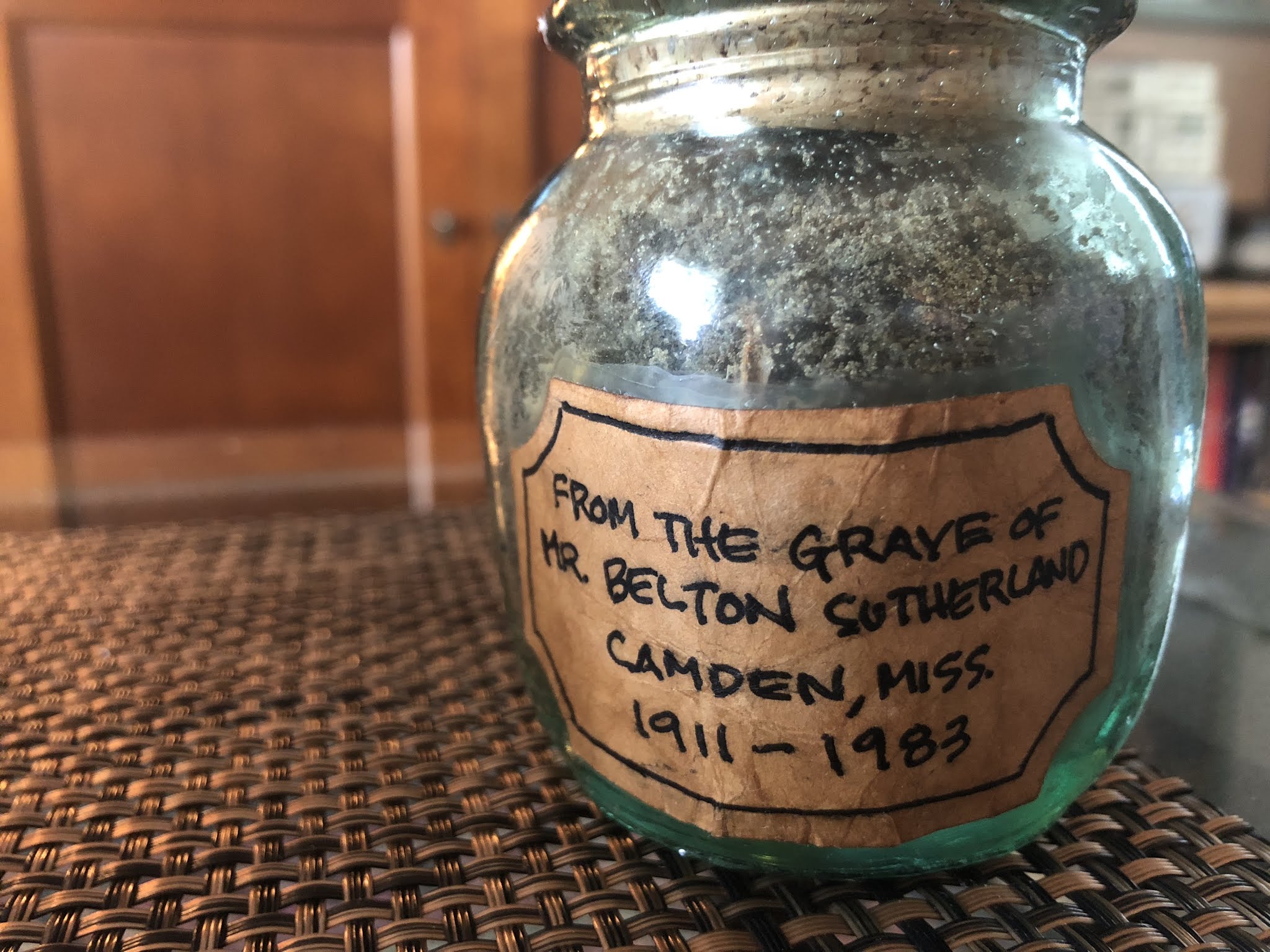 Glass container of dirt from the grave of Belton Sutherland. Given by Joe Austin to the Mt. Zion Memorial Fund